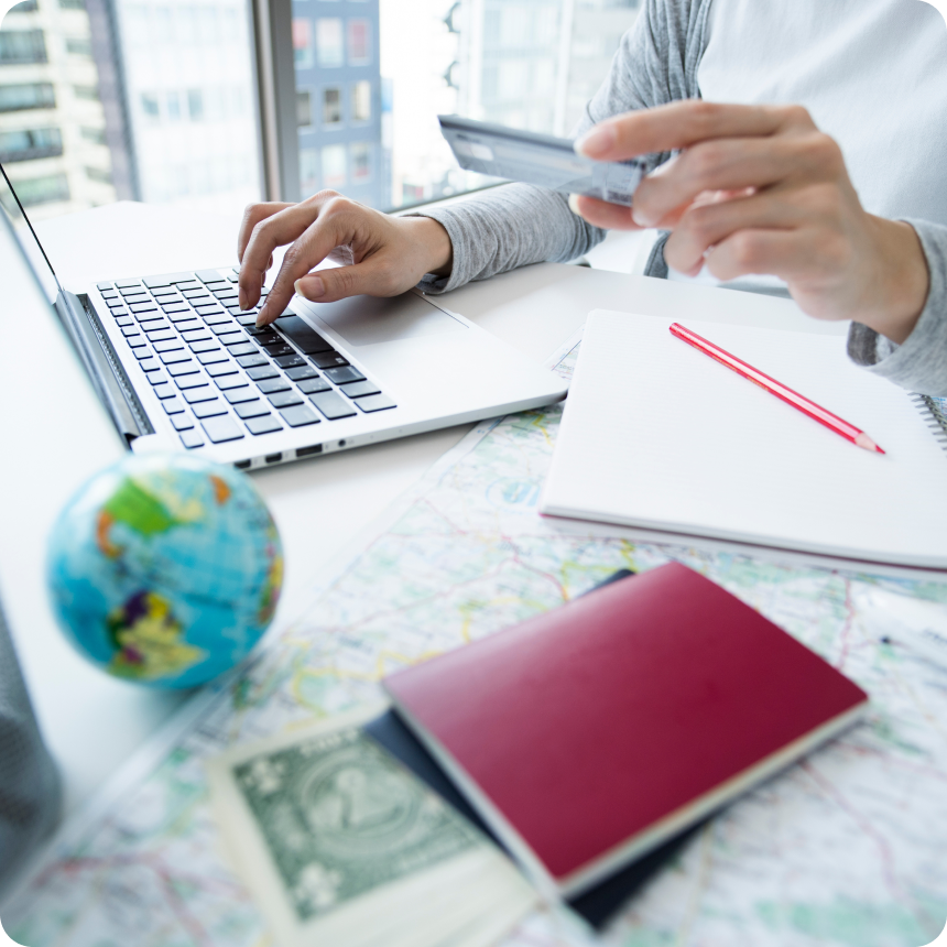 テーブルの上にノートや地図がありパソコンを触っている女性の手元